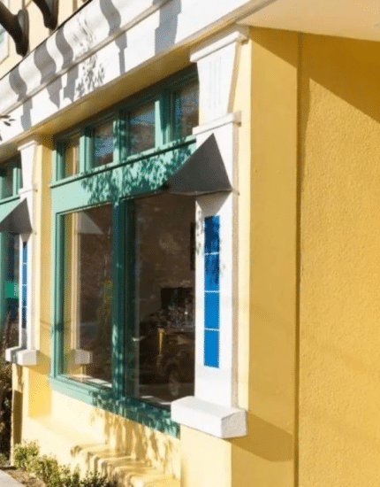 Yellow building with green-trimmed windows at 425, next to a sidewalk with trees; a Starbucks sign and outdoor seating are visible in the background.